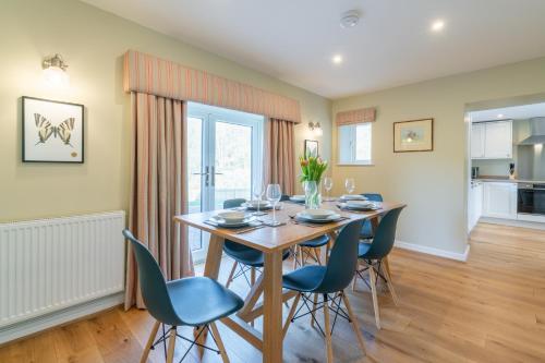 a dining room with a wooden table and blue chairs at Quarry Lodge in Lydney