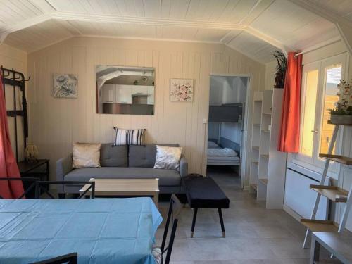 ein Wohnzimmer mit einem Sofa und ein Zimmer mit einem Bett in der Unterkunft Cottage les petites voiles plage in Agon Coutainville