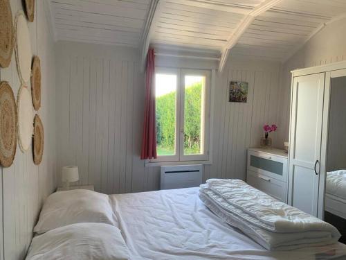 ein Schlafzimmer mit einem weißen Bett und einem Fenster in der Unterkunft Cottage les petites voiles plage in Agon Coutainville