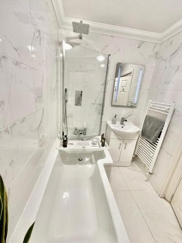 a white bathroom with a sink and a mirror at Glen Fern Lodge - Garden Apartment with Parking - Heart of Bournemouth Town Centre - Close to Beach - Darts and Table Football - Sleeps 11 in Bournemouth