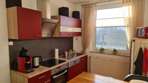 a small kitchen with red cabinets and a window at Brandenburgblick in Herleshausen