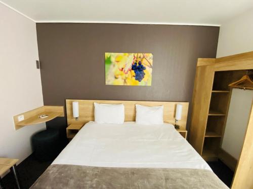 a bedroom with a bed and a painting on the wall at Hotel Wood Inn Bordeaux Aéroport in Mérignac