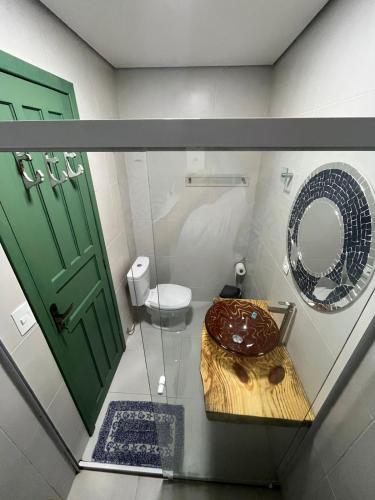 a bathroom with a toilet and a green door at Pousada Guaricana in Pontal do Paraná
