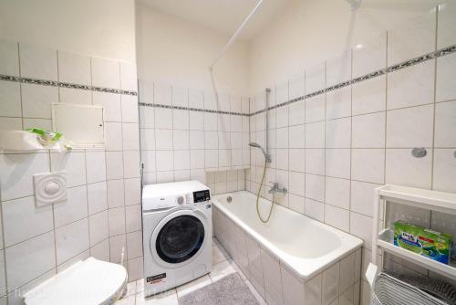 een badkamer met een wasmachine en een bad bij Apt Nikola 3 Zimmer Balkon 72qm Waschtrockner TV Vollausstattung zentral in Fürstenwalde