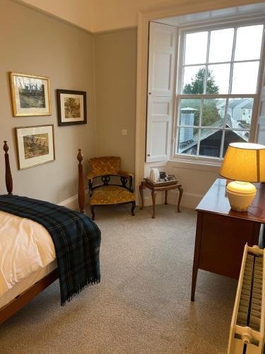 um quarto com uma cama, uma cadeira e uma janela em The Garret Hotel em Kirkcudbright