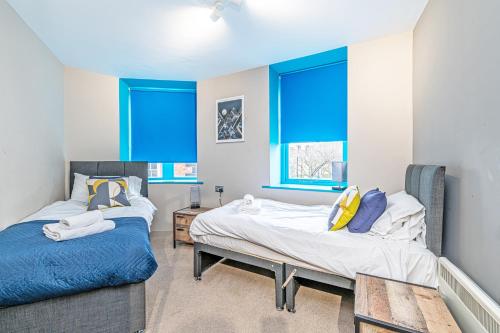 two beds in a room with blue windows at Wigan Central Serviced Apartments in Wigan