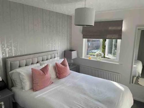 a bedroom with a white bed with pink pillows at Alma Court Retreat Freshwater IOW in Freshwater