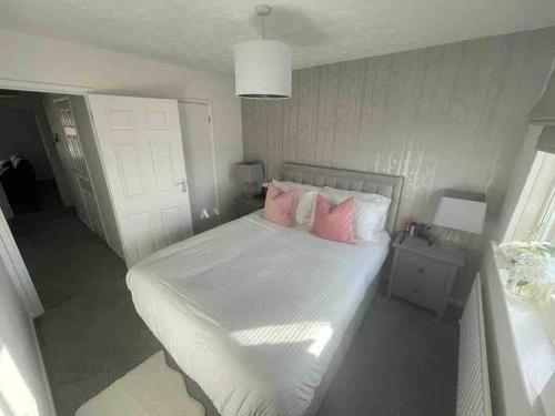 a bedroom with a white bed with pink pillows at Alma Court Retreat Freshwater IOW in Freshwater