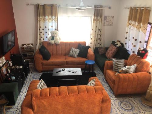 uma sala de estar com sofás laranja e um urso de peluche sentado num sofá em Anayah House em Kiembi Samaki