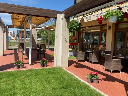 een patio met stoelen, tafels en bloemen voor een gebouw bij Hotel Legend in Dunajská Streda