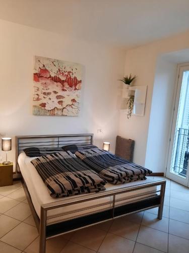 a bed in a bedroom with a painting on the wall at Fantastic Lake Como apartment in Musso