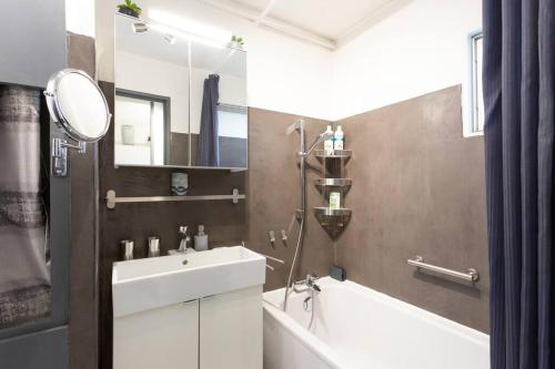 W łazience znajduje się umywalka, wanna i lustro. w obiekcie Chez Claude - Joli studio cabine climatisé avec parking et piscine w mieście La Grande-Motte
