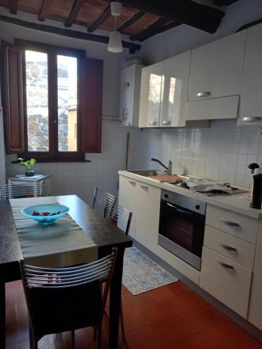 una cocina con armarios blancos y una mesa con sillas. en Rocci al 17, en Montalcino
