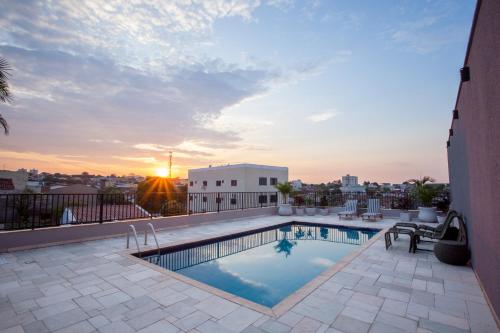 a pool on the roof of a building with the sunset at Gelps Hotel in Rio Verde