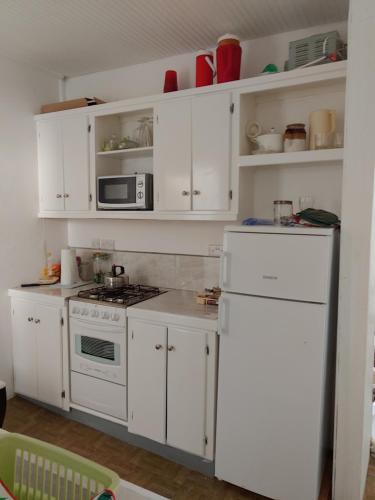 a kitchen with white cabinets and a white refrigerator at A Jewel of A Chalet in Roseau