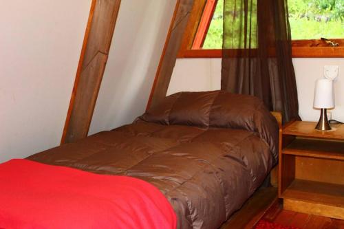 a small bed in a room with a window at Refugio del Pollux- Coyhaique- Orillas Lago Pollux in Coihaique