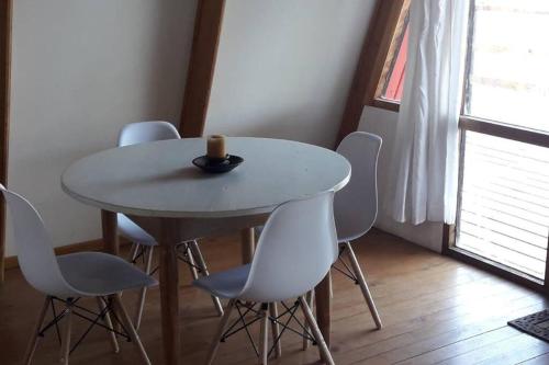 a table with white chairs and a candle on top at Refugio del Pollux- Coyhaique- Orillas Lago Pollux in Coihaique