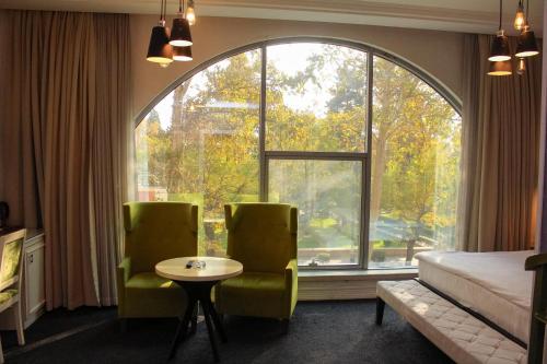 a room with a bed and two chairs and a window at Dondar Hotel Formula 1 View in Baku
