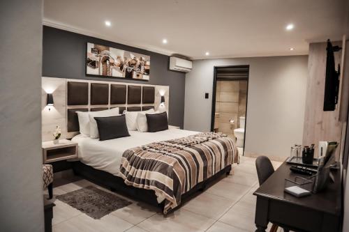 a bedroom with a large bed and a desk and a desk at Cascades Guest Lodge in Nelspruit