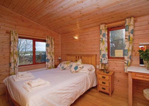 a bedroom with a bed in a log cabin at Nunland Hillside Lodges 