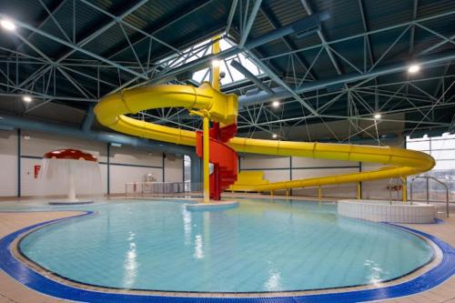 uma piscina com um escorrega de água amarelo e vermelho em Luxury Lodge @ Hoburne Devon Bay em Torquay