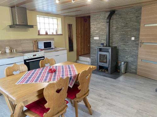 y cocina con mesa de madera, sillas y fogones. en Gîte des cigognes, en Sermersheim