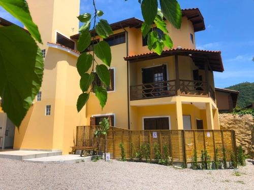 a yellow house with a fence in front of it at Studios Aromas do Campeche - Floripa in Florianópolis