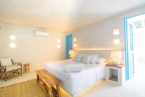 - une chambre avec un grand lit blanc et une chaise dans l'établissement Hotel Fenix Beach Cartagena, à Tierra Bomba