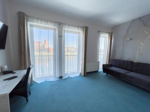 a living room with a couch and two large windows at Hotel Poleski in Krakow