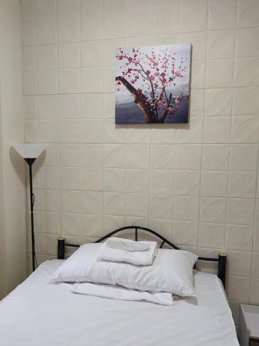 ein Schlafzimmer mit einem Bett mit weißer Bettwäsche und einem Baum in der Unterkunft Apartelle near Philippine Arena in Bulakan