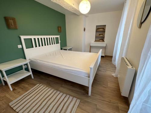 1 dormitorio con cama blanca y pared verde en Chez Alice - Isigny le Buat, en Isigny-le-Buat