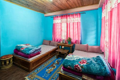 een blauwe kamer met 2 bedden en een tafel bij 3 Sisters' Homestay in Ravangla