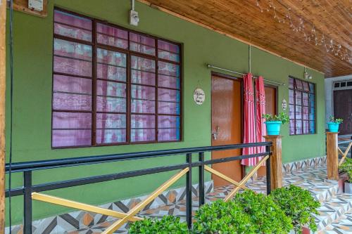 a green house with windows and a balcony at 3 Sisters' Homestay in Ravangla