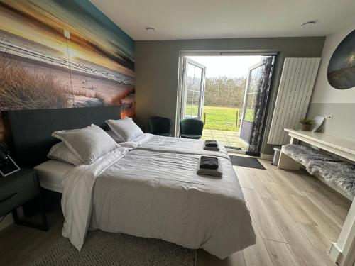 a bedroom with a large bed and a large window at Logies Boszicht Texel in De Koog