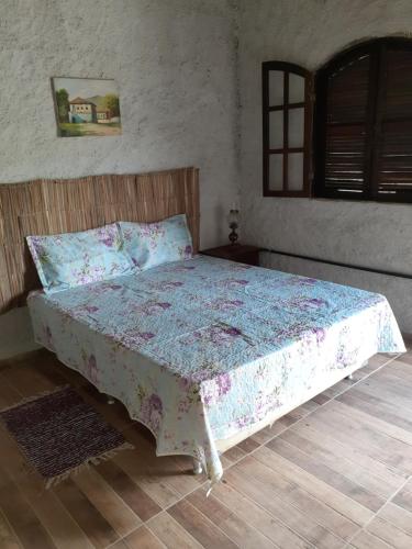 a bedroom with a bed with a floral bedspread at Fazenda Águas Claras in Mendes