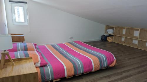 ein Schlafzimmer mit einem Bett mit einer bunten gestreiften Bettdecke in der Unterkunft Adorable petite maison au coeur du Luberon in Villelaure