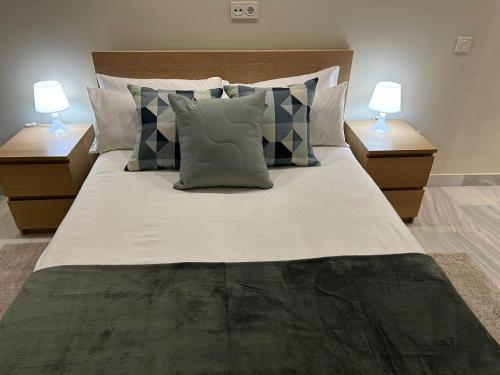 a large bed with pillows and two lamps on tables at Apartamento Fibes-Congresos Parking Gratis in Seville