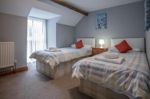 um quarto com 2 camas e uma janela em Rose Coach House - 3 Bedroom Cottage - Pendine em Pendine