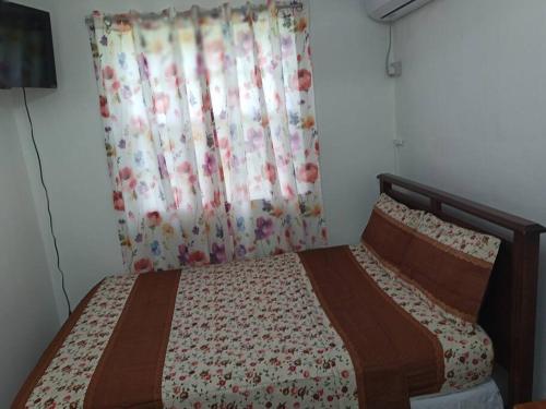a bedroom with a bed with a flowered blanket and a curtain at Casa Arturo in Mount Gay
