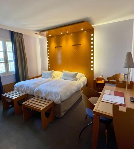 a hotel room with a large bed and a desk at Hôtel Au Logis des Remparts in Saint-Émilion