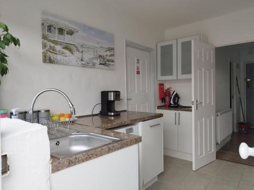 a kitchen with white cabinets and a sink at We love Henbury in Bristol