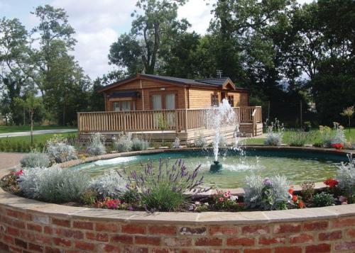 a log cabin with a fountain in front of a house at York House Country Park in Thirsk