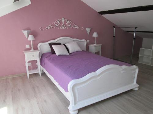 a bedroom with a white bed and purple walls at Lou Quinsou in Bordezac