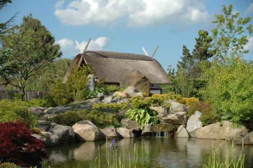 une maison au toit de chaume avec un étang dans un jardin dans l'établissement First Camp Aarhus - Jylland, à Aarhus