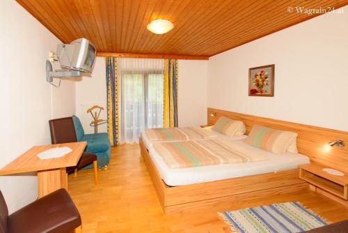 Schlafzimmer mit einem Bett, einem Schreibtisch und einem TV in der Unterkunft Schrahlehen in Wagrain