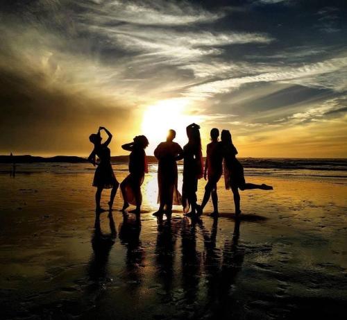 a group of people walking on the beach at sunset at Europa mirlef t aventur Guest House in Mirleft