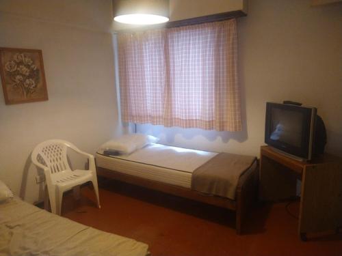 1 dormitorio con 1 cama, TV y silla en Departamento 4 personas en Mar del Plata