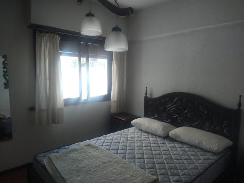 1 dormitorio con 1 cama con 2 almohadas y ventana en Departamento 4 personas en Mar del Plata