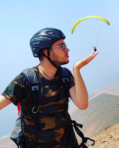 a man wearing a helmet is flying a kite at Europa mirlef t aventur Guest House in Mirleft