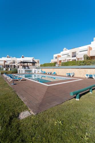 a swimming pool with a wooden deck next to a building at Azure - Vista para o Oceano by Smarthomes in São Martinho do Porto